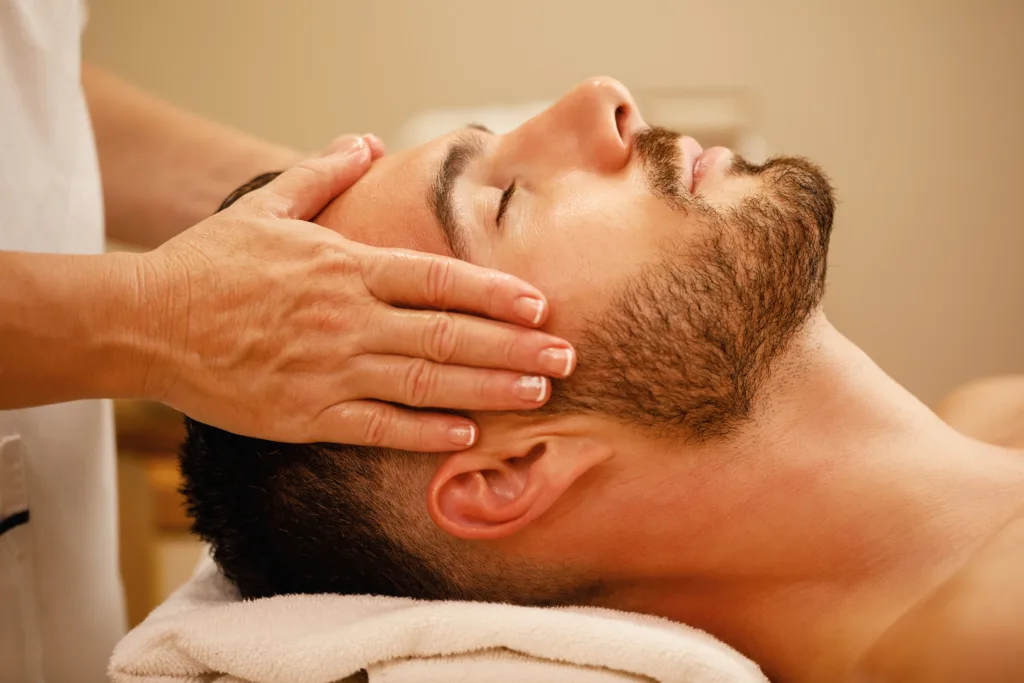 close up of relaxed man during head massage at spa center.